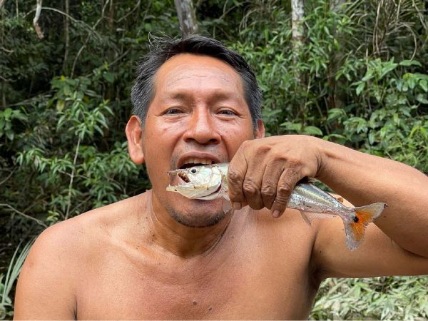 Hombre sosteniendo una piraña en la selva amazónica, mostrando las tradiciones de pesca local en Iquitos, Perú.
