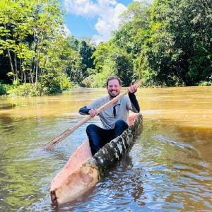 Turista remando en una canoa artesanal en un río rodeado por la exuberante selva amazónica cerca de Iquitos.