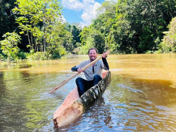 Turista remando en una canoa artesanal en un río rodeado por la exuberante selva amazónica cerca de Iquitos.