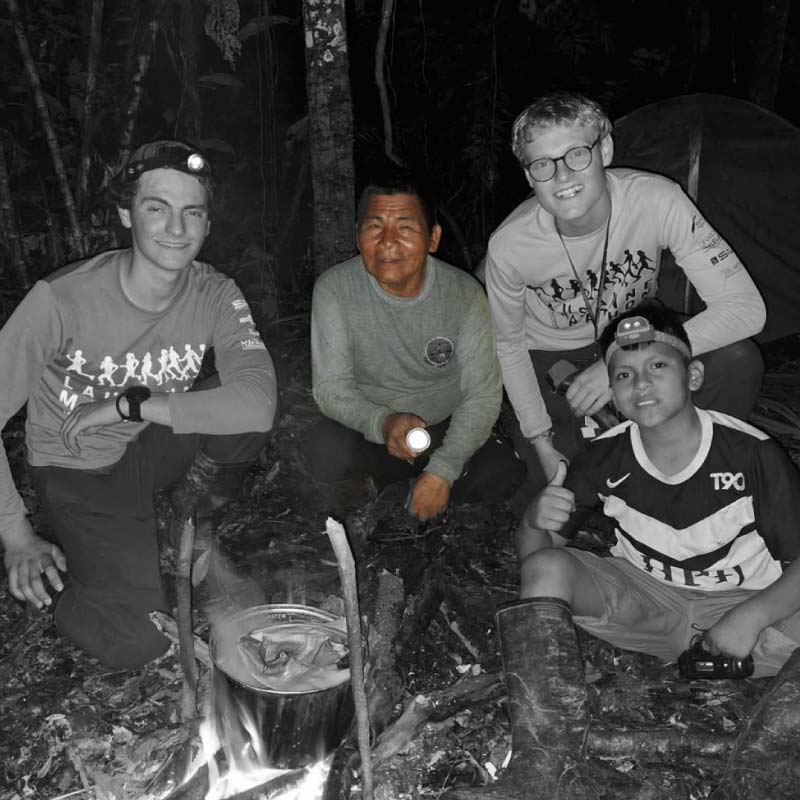 Grupo de turistas en una experiencia de camping nocturno en la selva amazónica cerca de Iquitos, guiados por expertos locales.