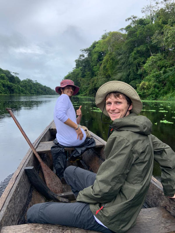 Dos personas navegan en canoa por un río dentro de la Reserva Nacional Pacaya Samiria, rodeados de selva tropical y vegetación acuática.