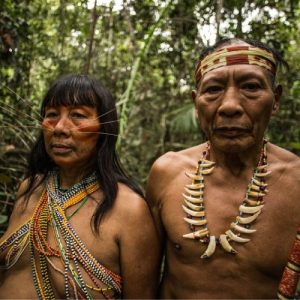 Primer plano de una mujer de la etnia Matsés con pintura facial roja y "bigotes" de fibra vegetal, representando al jaguar.